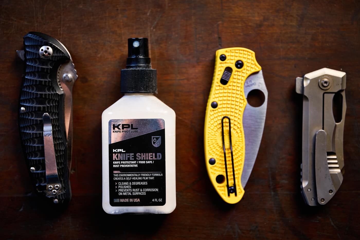 Eine Detailaufnahme von drei zusammengeklappten Messern und einer Flasche Reinigungsmittel KPL Knife Shield